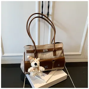 Detail of canvas tote bag with brown leather pockets, metal lock and plush bear charm