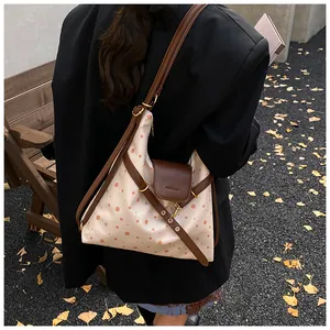Outdoor lifestyle shot of a cream polka dot shoulder bag with brown leather straps