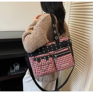 Close-up of red houndstooth punk crossbody bag with metal rivets and chain details