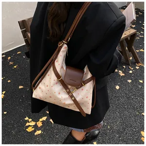 Close-up of beige canvas shoulder bag with pink dots and brown leather flap detail