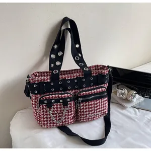 Detail of red houndstooth punk bag with silver metal eyelets, studs and chain accents