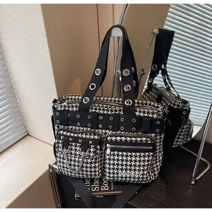 Macro detail of houndstooth punk bag featuring metallic eyelets and dual zipper pockets