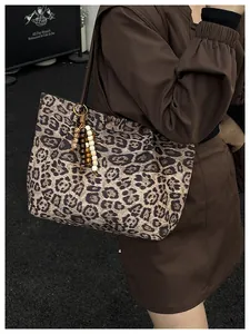 Close-up of leopard print tote bag featuring wooden bead tassel and textured canvas material