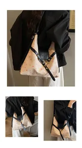 Detail of red polka dot canvas tote with black leather straps and brand logo