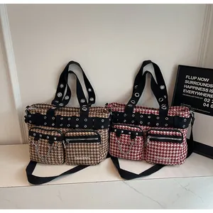 Detail of houndstooth tote bag with silver studs and chain straps in brown and red colors
