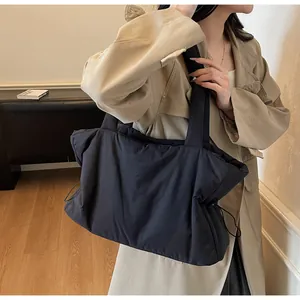 Detailed view of the side drawstring on a large quilted nylon tote bag worn by a model
