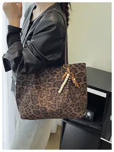 Detail of leopard print tote bag featuring brown bead tassel charm and round straps
