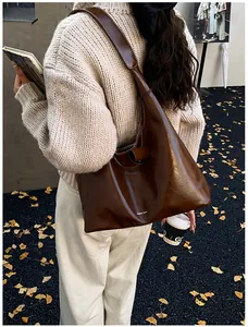 Detail of dark brown leather hobo bag with contrast stitching and white brand logo