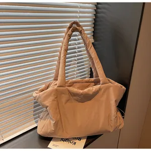 Detail of beige quilted down tote bag with drawstring texture on windowsill