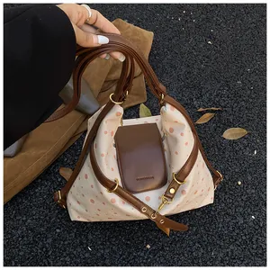Close-up of canvas polka dot shoulder bag with brown leather strap and metal buckle