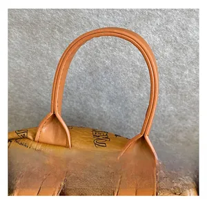 Detail of the reinforced top handle on a brown pebbled leather backpack with letter prints