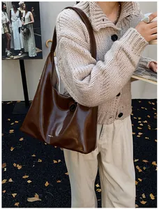 Detail of a deep brown oil wax leather shoulder bag styled with an autumn knit cardigan