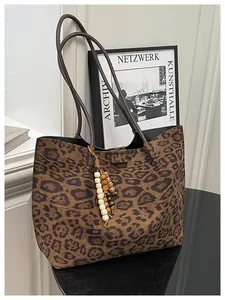 Detail of leopard print tote bag featuring wooden bead tassel and slender shoulder straps