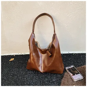 Close-up of brown oversized faux leather hobo bag with wide shoulder strap for commuting