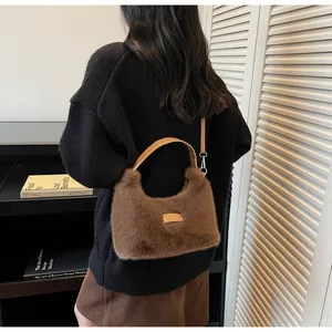 Détail du sac à main en fausse fourrure marron avec plaque dorée et anses en cuir