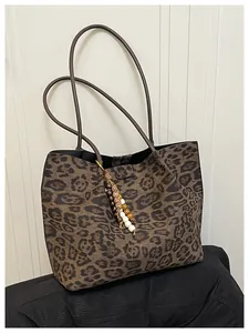 Detail of leopard print tote bag with vintage bead charm and brown leather straps