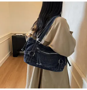 Détail du sac croissant en denim bleu avec broderie tendance et boucles métalliques