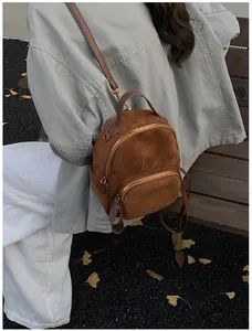 Nahaufnahme eines mini braunen Wildleder-Rucksacks mit schmalem Lederriemen am Model