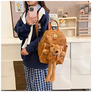 Brown faux leather backpack featuring all-over monogram prints and a plush bear pendant