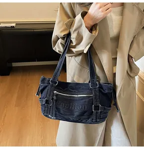 Détail du sac cabas en denim bleu avec texte Fashion en relief et garnitures argentées