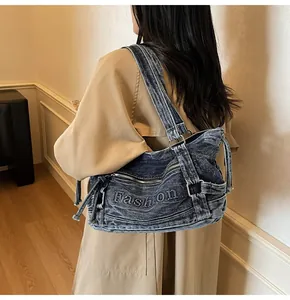 Détail du sac croissant en denim bleu avec broderie vintage et anneaux argentés