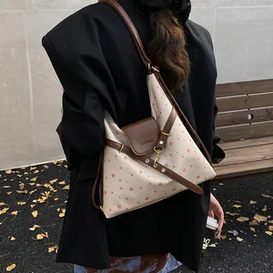 Polka dot canvas shoulder bag with brown leather accents and gold hardware on a model
