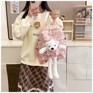 Detail of pink PU leather backpack with cartoon prints and a large plush bear decoration