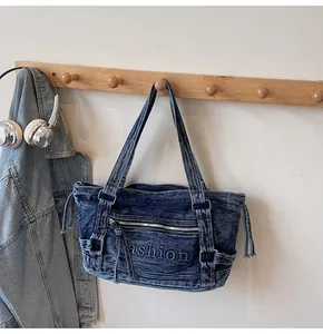 Détail du sac fourre-tout en denim délavé bleu foncé avec broderie et cordons latéraux
