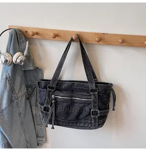 Détail du sac cabas croissant en jean noir avec broderie Fashion et zips métalliques