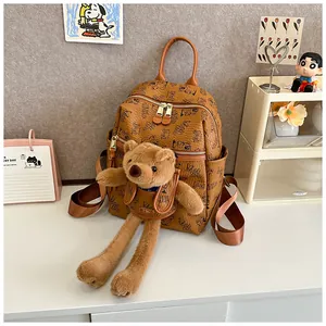 Close-up of brown leather backpack with retro patterns and a cute plush bear charm