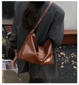 Detailed view of deep brown glossy leather shoulder bag with gold semicircular buckle