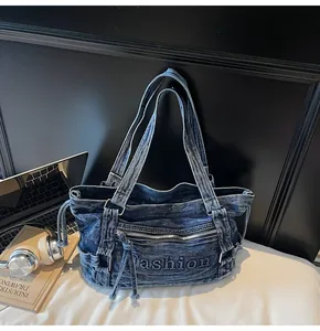 Gros plan du sac demi-lune en jean bleu avec lettrage Fashion et détails zippés