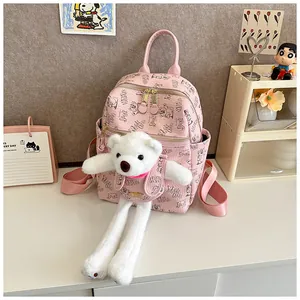 Detailed view of pink backpack featuring cute cartoon bear prints and plush doll pendant