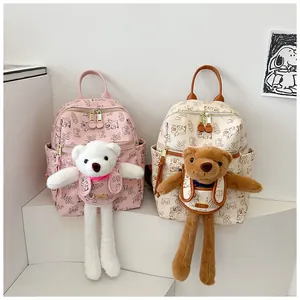 Detail of pink and off-white backpacks with cute bear plush charms and teddy pattern