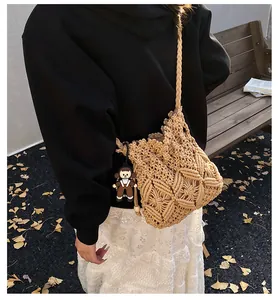 Detail of woven crossbody bucket bag with hollow pattern and a cute doll pendant