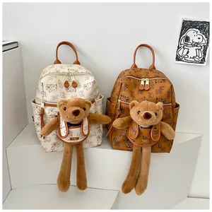Close-up of stylish printed backpacks featuring plush bear charms and multi-zipper pockets