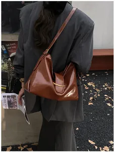 Detail of a brown glossy leather shoulder bag with a gold ring buckle in a street fashion style