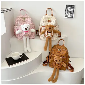 Close-up of printed mini backpacks in pink and beige with cute teddy bear dolls