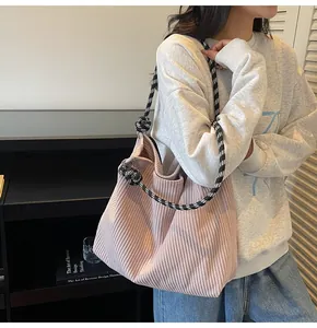 Close-up of pink corduroy tote bag with black and white braided rope handles on a model