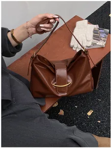 Detail of soft dark brown leather tote bag with vintage gold metal clasp on wood