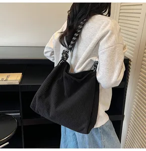 Detail of black corduroy tote bag featuring a decorative black and white checkered strap