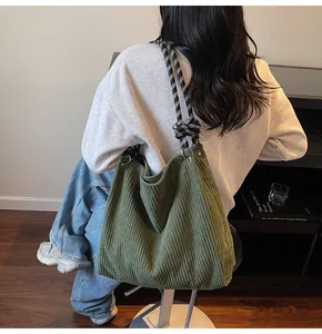 Close-up of green corduroy tote bag with textured stripes and black-white checkered cord handle