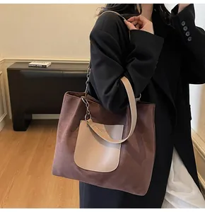 Detail of suede tote bag featuring leather front pocket and chain shoulder strap