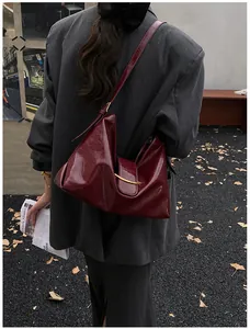 Deep red patent leather underarm bag with glossy cloud-like folds and gold metal bar