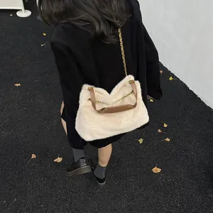 Schicke beige Plüsch-Umhängetasche mit goldener Kette auf Straße mit Ginkgo-Blättern