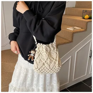 Detail of hand-woven cream bucket bag featuring geometric patterns and a cute doll charm