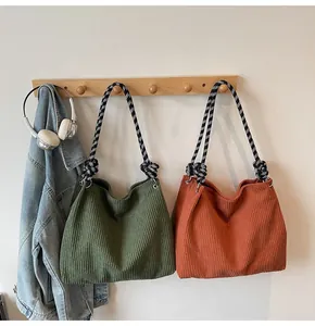 Detail of corduroy crossbody bags with contrast woven rope straps in green and orange