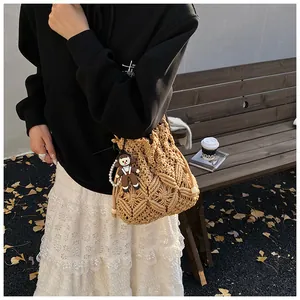 Detail view of woven bucket bag featuring diamond patterns and cute doll pendant accessory