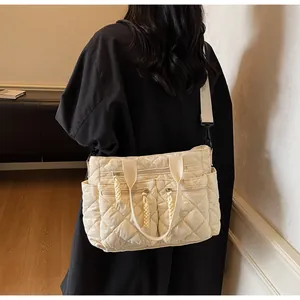 Detail of beige quilted nylon shoulder bag with multiple zip pockets and woven pullers