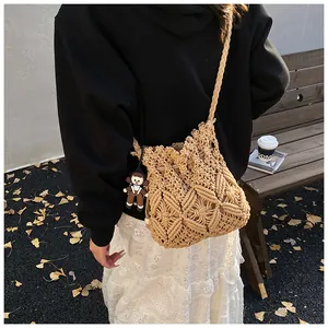 Detailed outdoor shot of beige hand-woven bucket bag with star pattern and cute charm